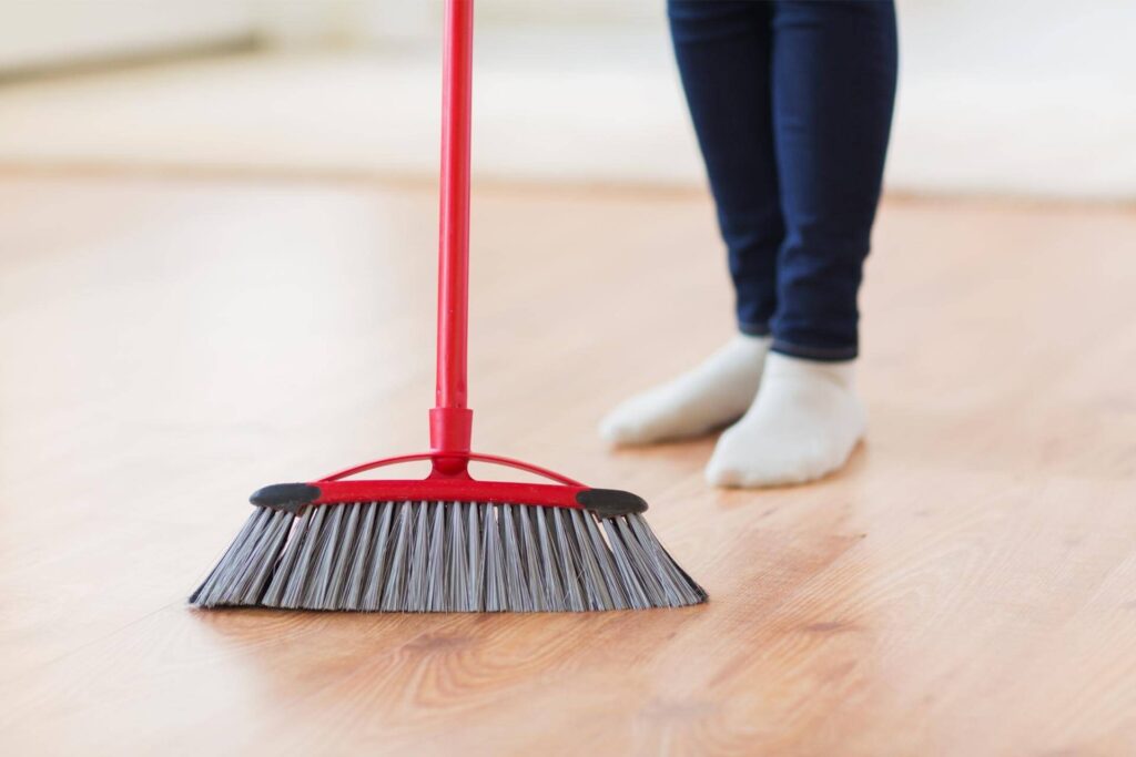 pulizia pavimenti in legno con la scopa prima del lavaggio
